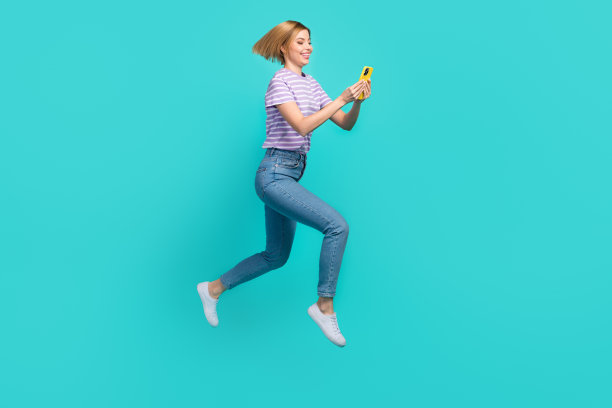 欢乐的漂亮女人的全尺寸照片鲍勃发型条纹t恤匆忙跑看智能手机孤立在蓝绿色的背景图片下载