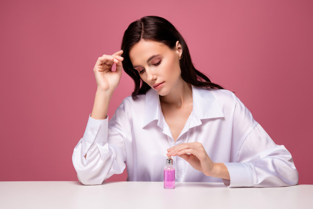 女孩的照片化妆师坐在桌子上看血清瓶孤立的粉红色背景图片下载