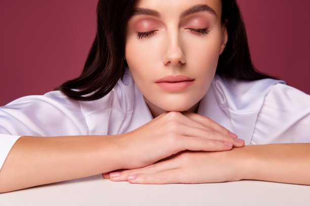女孩闭着眼睛看着相机的特写照片，手儿子桌子孤立的粉红色背景图片下载
