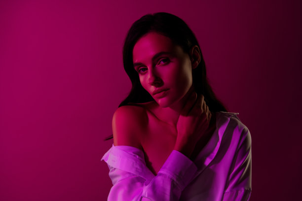 照片的女孩看相机触摸脖子手指感觉轻浮诱人孤立的粉红色背景图片下载