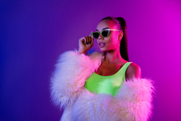 照片中迷人迷人的女士穿着皮草大衣，手戴墨镜，看起来空旷孤立的紫色背景图片下载