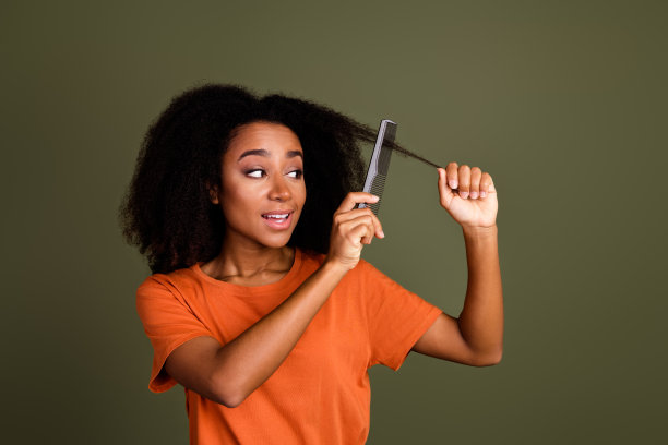 照片积极的好女人烫发的发型穿着橙色衬衫卷发梳不守秩序的头发孤立在黑暗卡其色背景图片下载