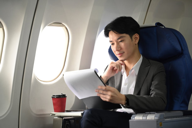 现代成功商人乘飞机旅行时阅读文件的肖像图片下载