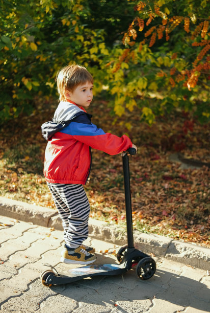 小男孩正在骑滑板车。季节性儿童活动运动。健康的户外活动或儿童运动。秋天或秋天的季节背景。图片下载