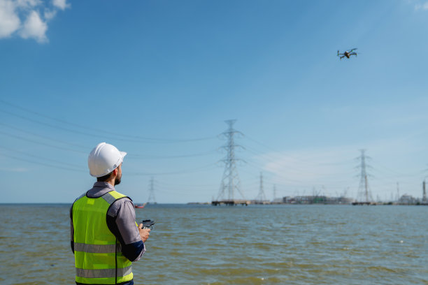 身穿安全背心的工程师操作无人机检查和测量输电线。技术员检查电站的定期维护。图片下载