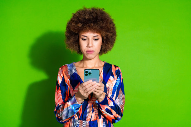 照片中漂亮可爱的女人穿着时尚的衣服，用苹果手机孤立在充满活力的绿色背景上图片下载