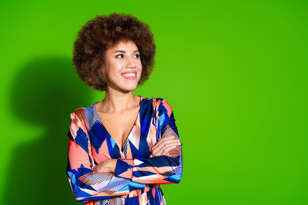 照片中华丽自信的女人穿着时尚的衣服，双臂交叉，在充满活力的绿色背景下看起来空无一物图片下载