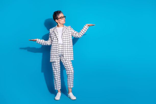 照片中，思想华丽的女人穿着白色时尚的衣服，双手抱着空白的空间，在蓝色的背景上提供隔离图片下载