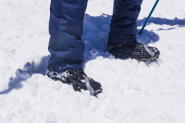 登山者的脚站在高山冰川上，穿着装有冰爪的登山靴图片下载