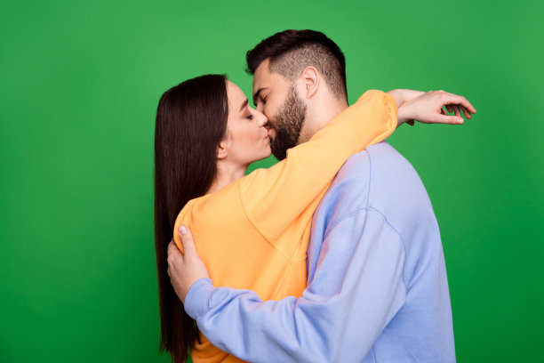 可爱迷人的甜蜜情侣拥抱和亲吻的照片，孤立的绿色背景图片下载