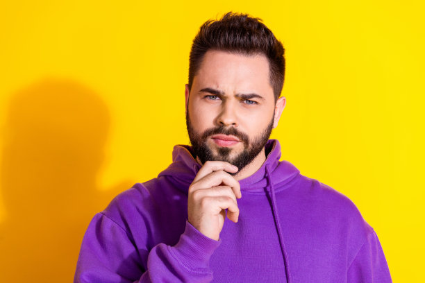 照片中英俊的头脑男人穿着时尚的衣服，手臂触摸下巴hmm孤立的黄色背景图片下载