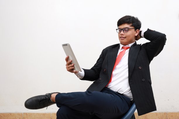 照片的经理首席执行官男子坐在椅子上使用设备平板电脑。隔离在白色背景上图片下载