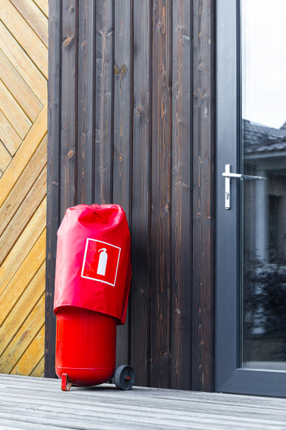 一个红色的移动灭火器站在房子附近，垂直照片图片下载