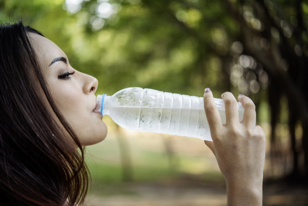 年轻女子喝水壶户外公园游客。亚洲女性饮用水瓶健康人快乐微笑。幸福美丽的亚洲中国女性拿着矿泉水瓶的生活方式图片下载