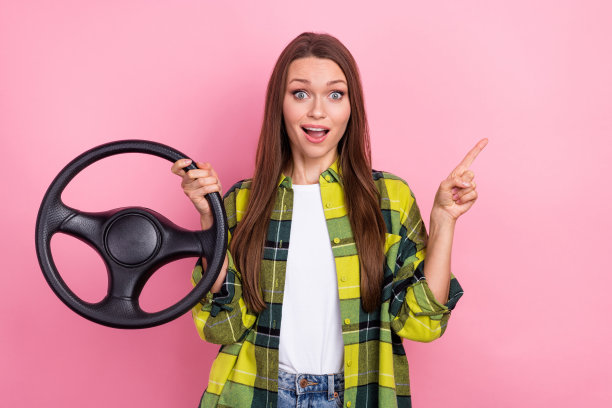 惊讶的女士手握方向盘的照片表明手指空白的空间孤立在粉红色的背景图片下载