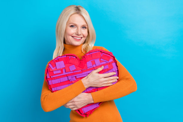 照片可爱的华丽积极的年长女士穿着时尚的衣服抱着大纸工艺品人物孤立的蓝色背景图片下载