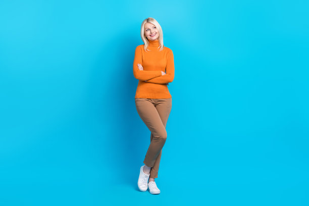 穿着橙色运动衫的开朗女子的全身照片，看着蓝色背景上孤立的折扣空间图片下载