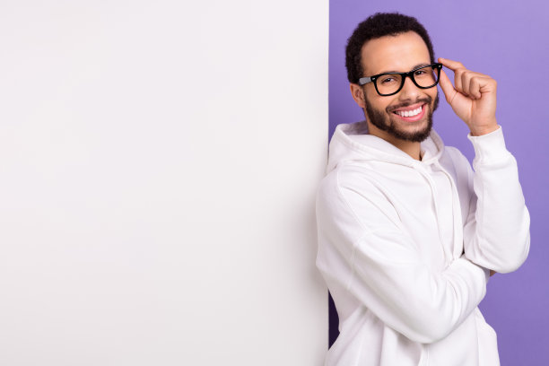 年轻的微笑企业家家伙的照片穿着白色运动衫触摸他的眼镜附近的大横幅空白空间孤立的紫色背景图片下载