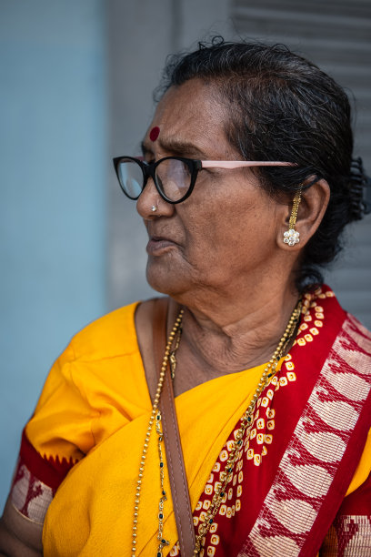 穿着黄色纱丽的印度老妇人。身着传统服饰的南亚印度教老妇人。街头的照片图片下载