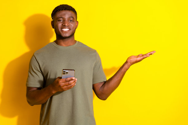 照片中，开朗有趣的好男人穿着卡其色时尚的衣服，拿着空荡荡的小玩意，孤立在黄色的背景上图片下载