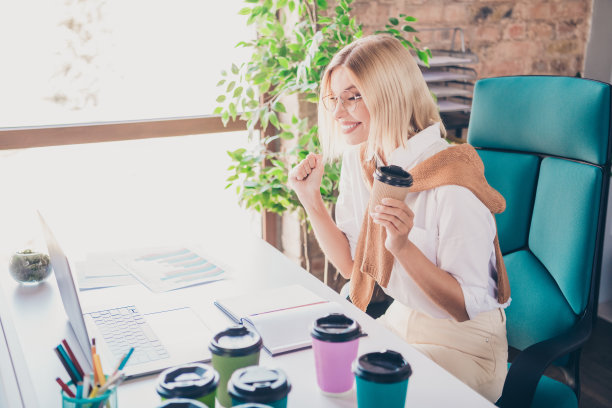 照片肖像可爱的年轻女士兴奋庆祝喝咖啡穿着时尚的服装现代职场办公室室内共同工作图片下载