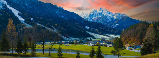 日落的景色与公路上的山村、绿草如茵的小山相映成趣。风景如画的旅行，季节性的乡村图片下载