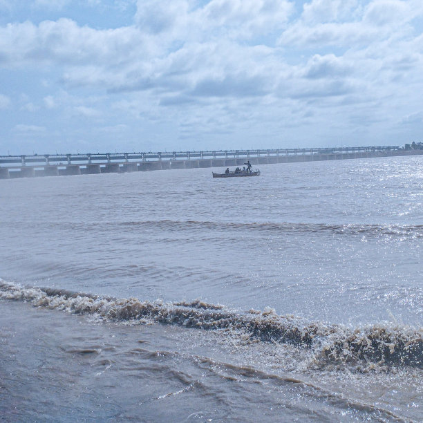 河滩与温柔的波浪和远处的船与水弹幕视图在夏天明亮的一天，水流，海岸景观，阳光明媚的天气图像库存照片图片下载