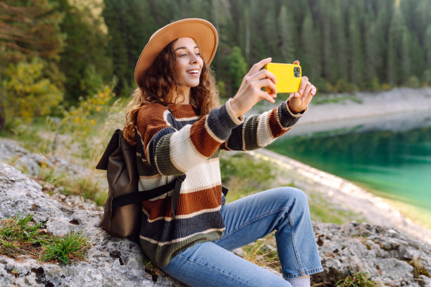 快乐的女人正在休息和拍摄惊人的风景与山的照片。图片下载