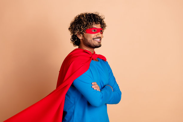 照片开朗积极的男人穿着服装幻想人物红色斗篷孤立在米色背景图片下载