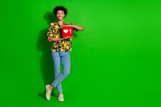 照片中开朗可爱的好男人穿着时尚的印花衣服，手持红牌，空白空间孤立在绿色背景上图片下载