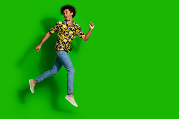 时髦的好积极的男人穿着时髦的夏季印花衣服跑空空间孤立的绿色背景的照片图片下载