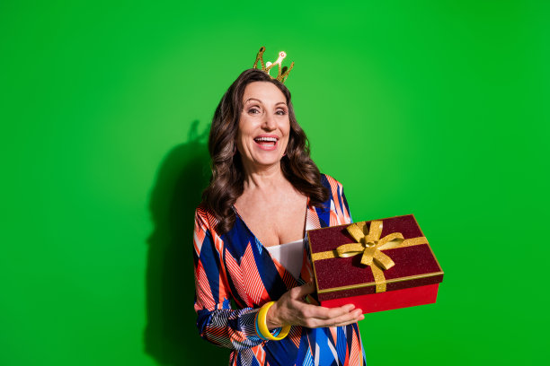 照片中迷人的正面女子穿着印花整体迪马抱着礼物空的空间孤立的绿色背景图片下载