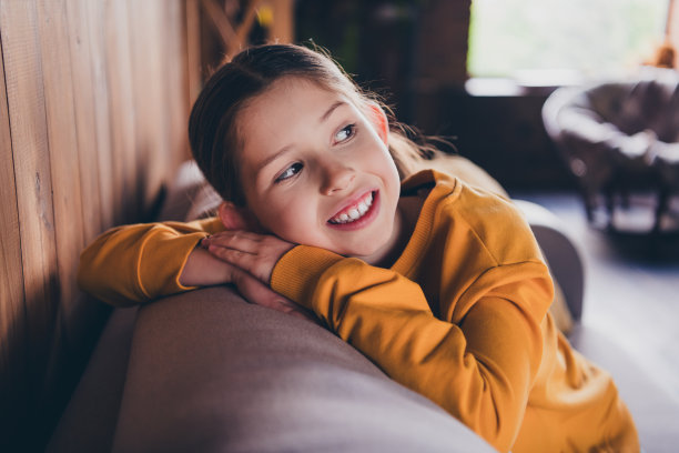 照片积极的好心情的小女孩穿着黄色套衫休息沙发在室内房子公寓房间图片下载