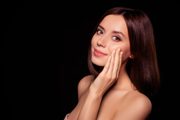 照片的漂亮女孩触摸脸温柔的皮肤看起来孤立的深黑色背景图片下载