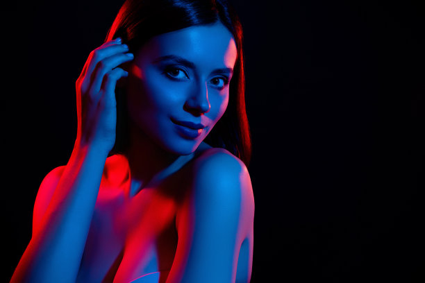 照片的漂亮女孩触摸手头发感觉轻浮孤立在黑暗的彩色霓虹背景图片下载