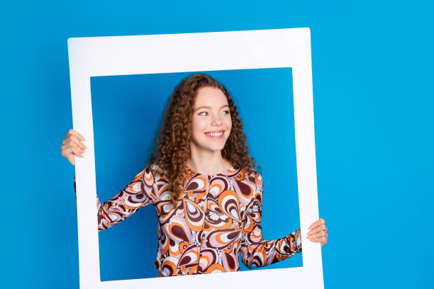 照片肖像可爱的年轻女士即时相框看空空间穿着时尚的彩色服装孤立在蓝色的背景图片下载