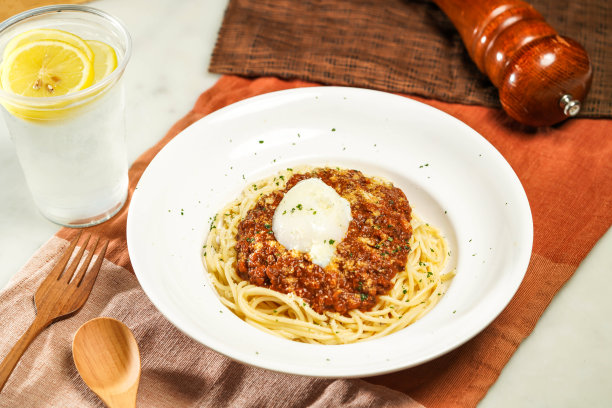 和牛肉酱配水煮蛋配柠檬水，木勺和叉子装在盘子里，单独放在餐巾纸上，餐桌侧面的意大利食物图片下载