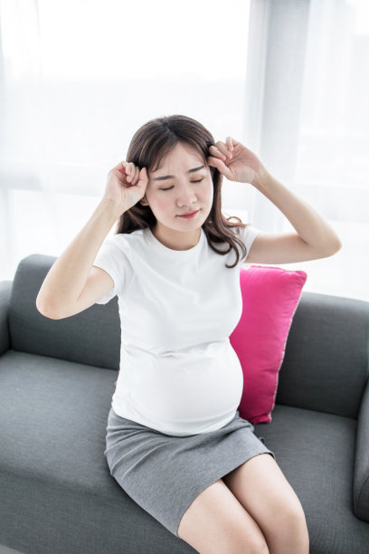 疲惫的孕妇。沮丧的怀孕女商人坐在办公室的工作地点，双手抱着头图片下载