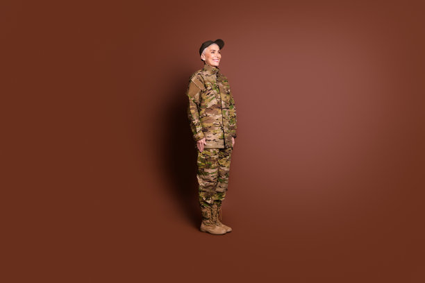 成年女性勇敢的女军人欢快的微笑穿着迷彩军装孤立的棕色背景照片图片下载