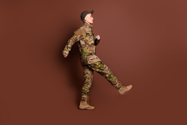 退休女士职业军官步行行军穿着迷彩军装孤立在棕色背景的全长照片图片下载