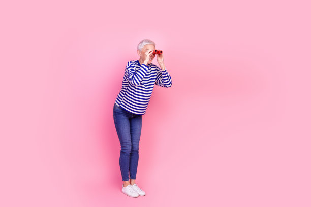 照片中迷人可爱开朗的高级女子穿着条纹时髦的衣服，在粉红色的背景上显得空旷孤立图片下载