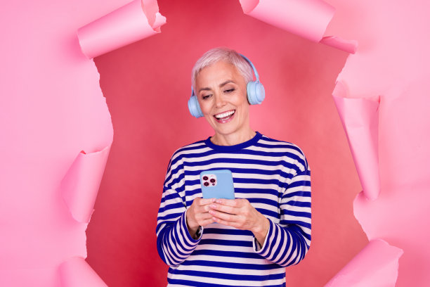 迷人可爱的漂亮女人穿着条纹时尚的衣服打破纸墙孤立的粉红色背景的照片图片下载