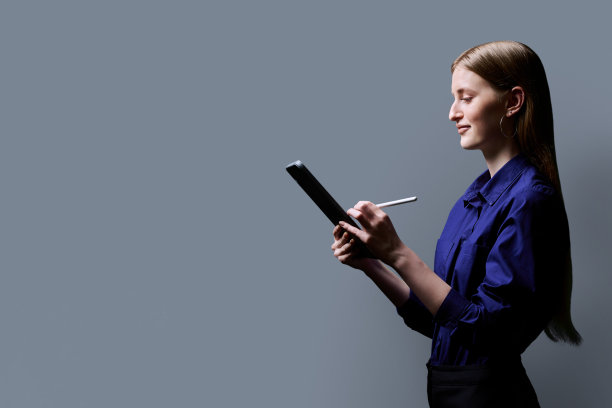 女大学生使用数码平板电脑，侧面视图，灰色背景图片下载
