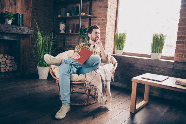 英俊的好心情的家伙穿着格子衬衫微笑着休息看书在室内房间家里房子的照片图片下载