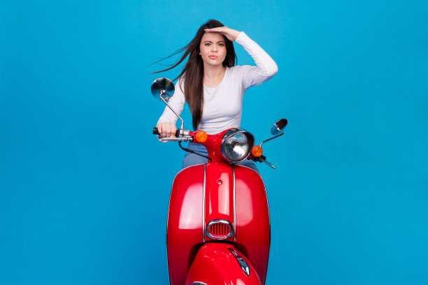 可爱的少女的照片肖像搜索方式额头骑摩托车穿着时尚的白色服装孤立的蓝色背景图片下载