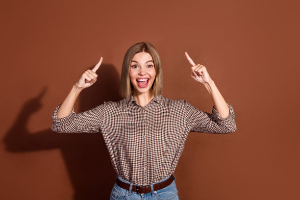 照片中的酷疯开朗的女人穿着时尚的衣服展示了空白的空间，在棕色的背景上孤立的新闻图片下载