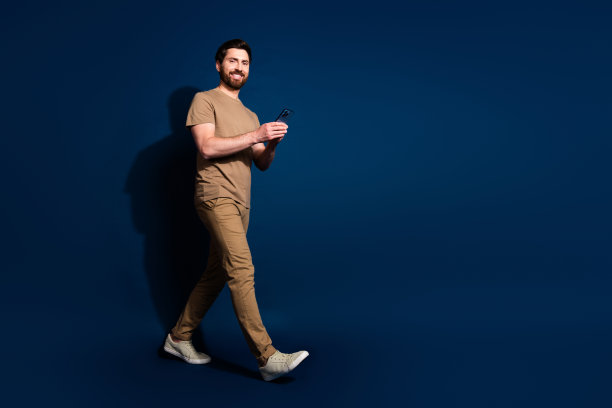 年轻英俊的黑发模特在深蓝色背景下用智能手机使用社交媒体的照片肖像图片下载