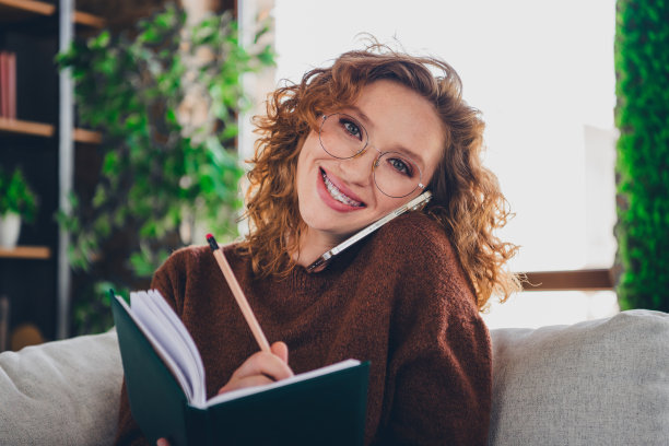 照片中迷人的女人穿着时髦的衣服，拿着计划者在家工作，在家里写计划图片下载