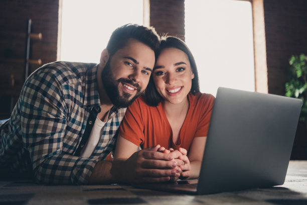 欢快可爱的年轻夫妇的照片躺在地板上上网本享受周末玩得开心买新公寓在室内在家里图片下载