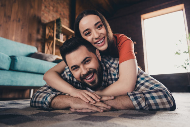 欢快可爱的年轻夫妇的全身照片躺在地板上拥抱享受周末玩得开心买新公寓在室内在家里图片下载